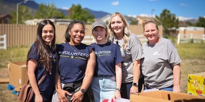 Five volunteers smiling next to food boxes.