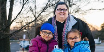 A mom and her two young children standing outside.