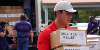 A person holding disaster relief boxes.