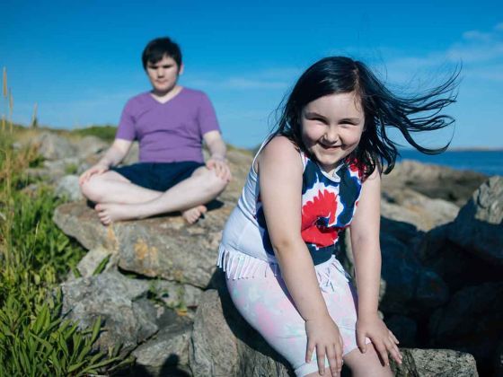 Gwen sitting on a rock by the beach.
