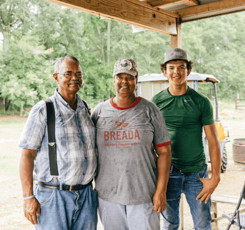 A family of farmers standing outside.