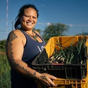 Kaui holds a bin of produce.