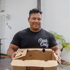 A man carrying a box while smiling.