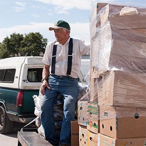 A man standing next to boxes of food.