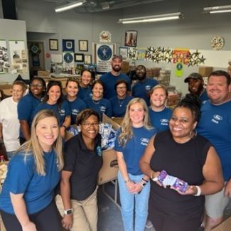 A group of people wearing blue shirts and posing for a photo.
