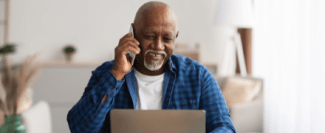 Man talks on the phone while looking at a computer screen