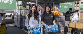 Two volunteers carrying cases of water bottles.